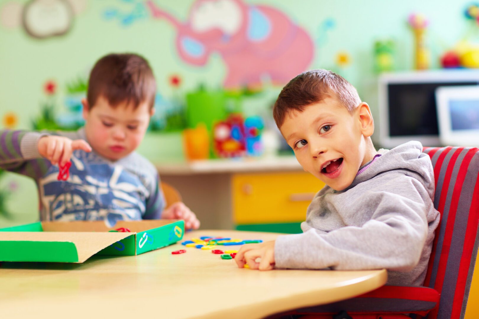 Two young boys engaged in play with colorful beads at a classroom table.