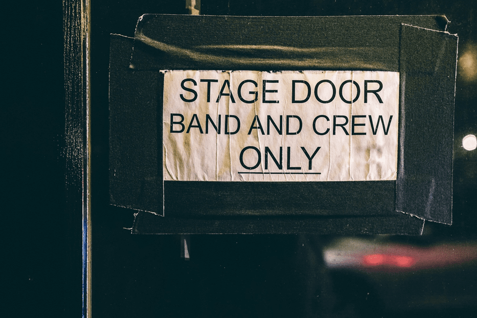 A sign on a door reading 'Stage Door Band and Crew Only'.