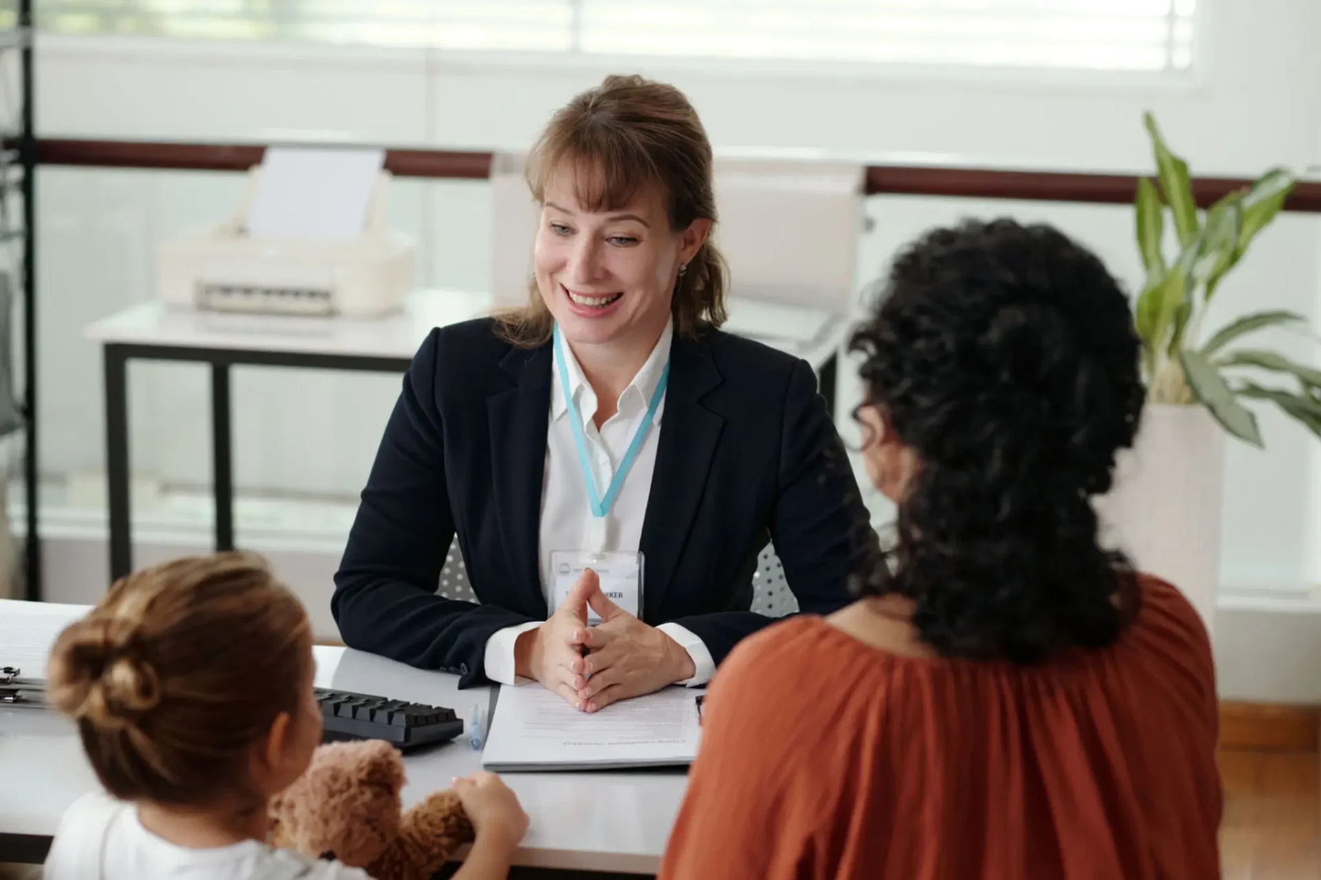 A professional woman smiling during a meeting with two clients.