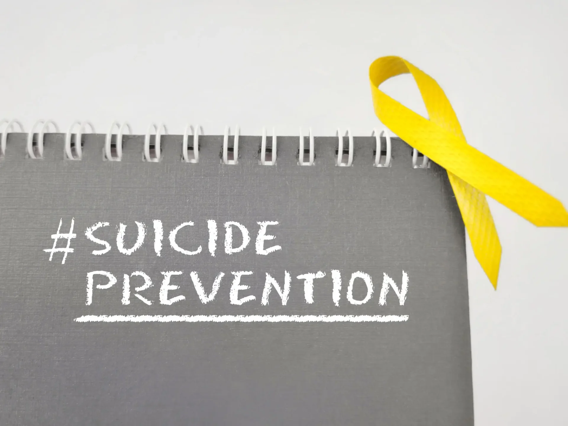 Yellow ribbon symbolizing suicide prevention on a notebook.
