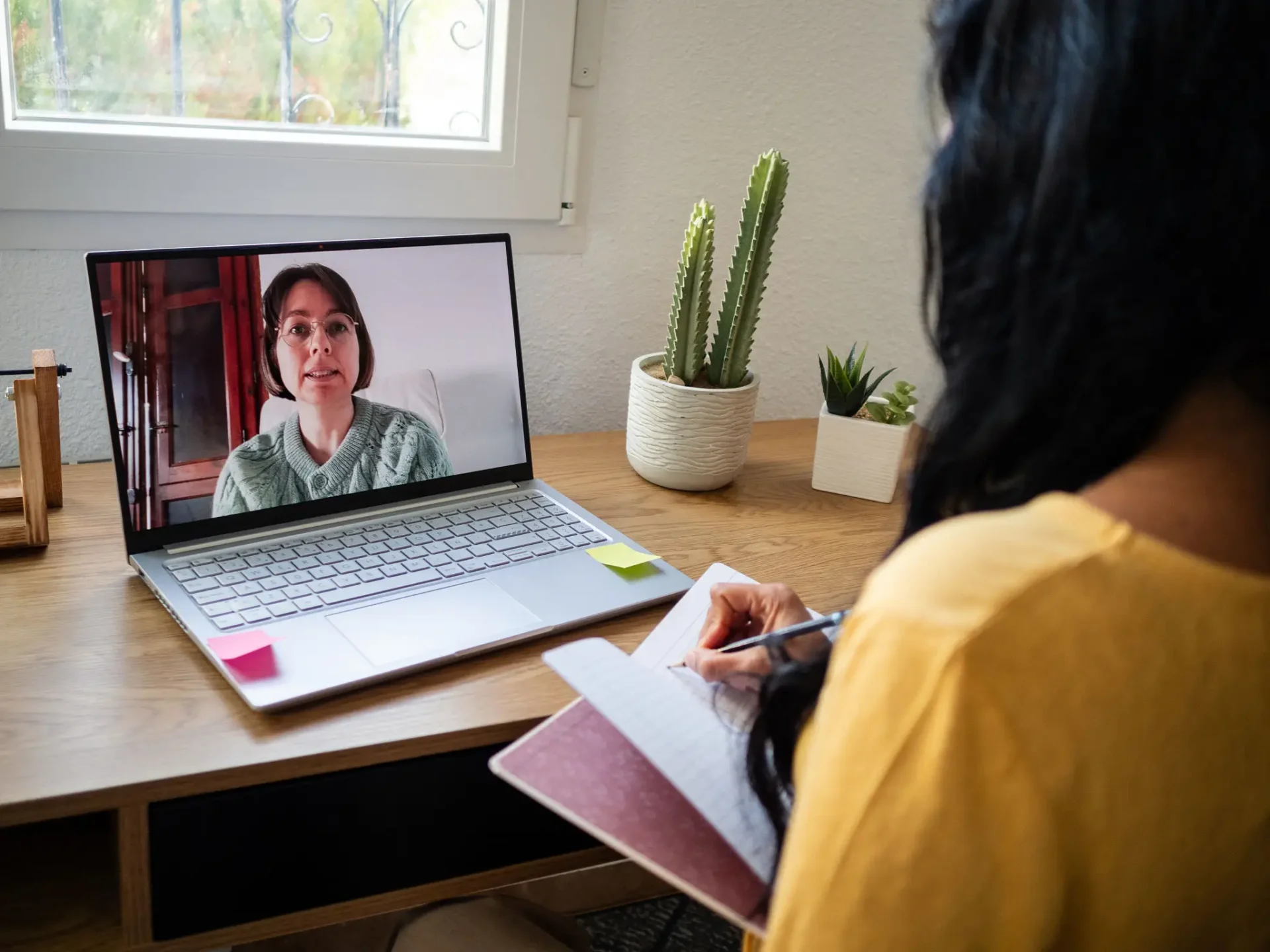 Person attending an online video call while taking notes.
