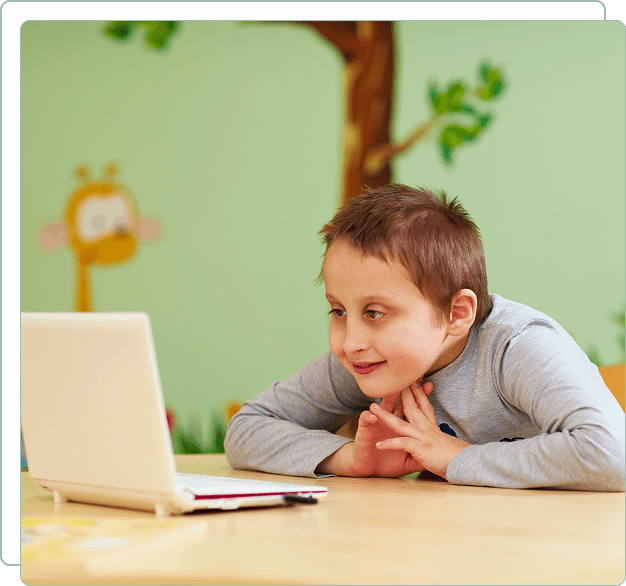 A boy smiling while looking at a laptop in a colorful room.