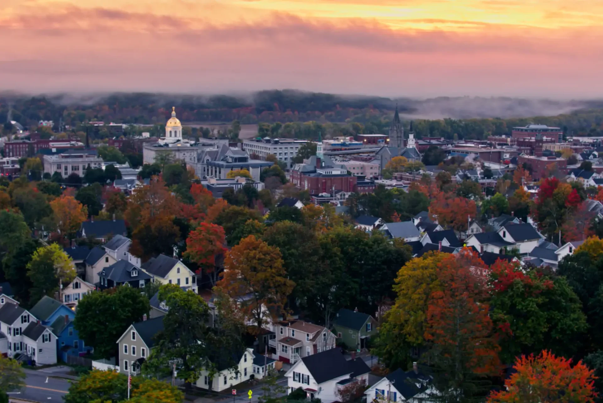 A vibrant town at sunset with colorful autumn trees and a prominent church steeple.