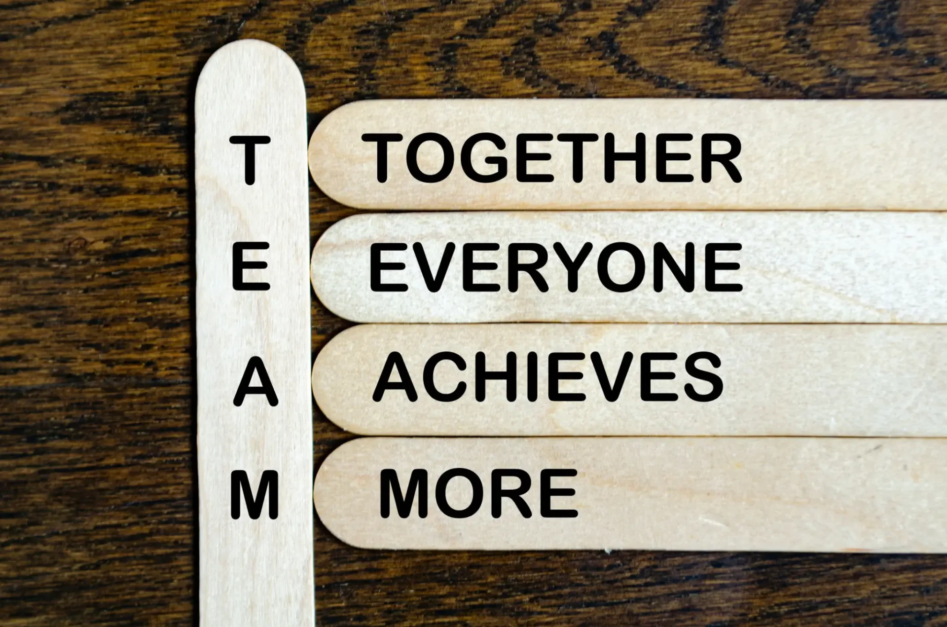 Wooden sticks forming a teamwork acronym with motivational words.