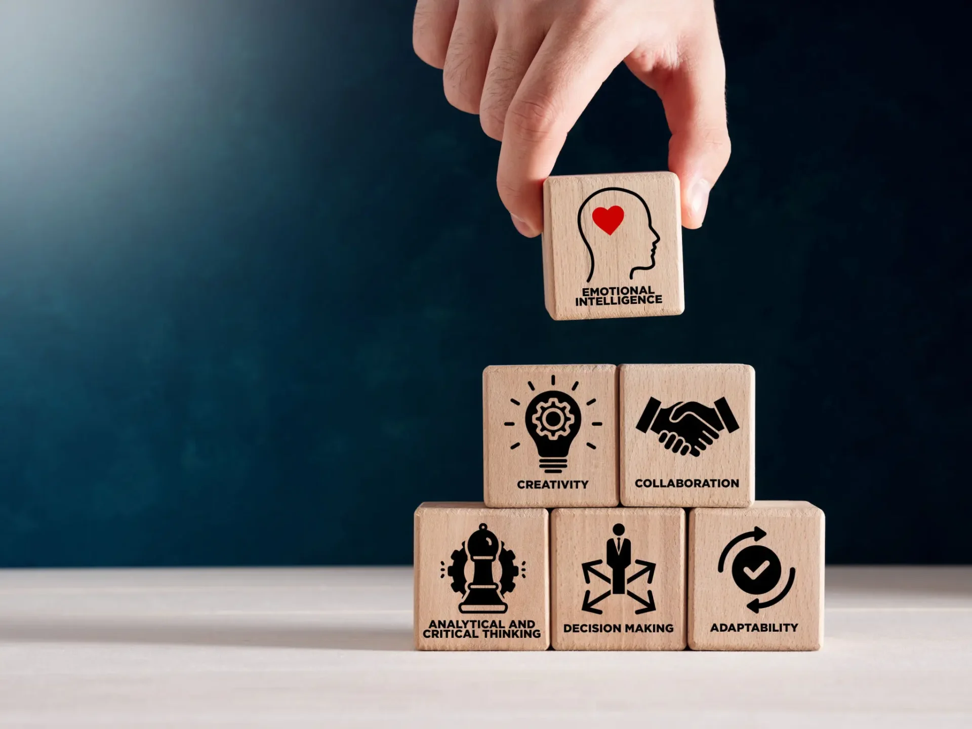 Hand stacking wooden blocks with business and love icons.
